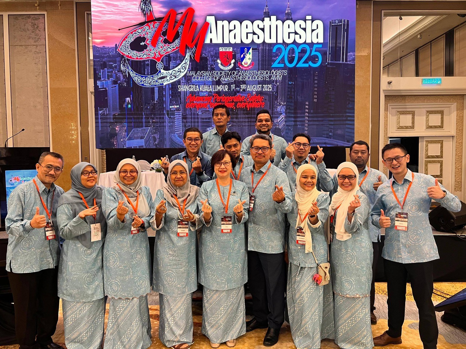 Professional event participants in coordinated batik shirts and kurung